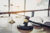 Gavel, scales, and law book on brightly lit table by window